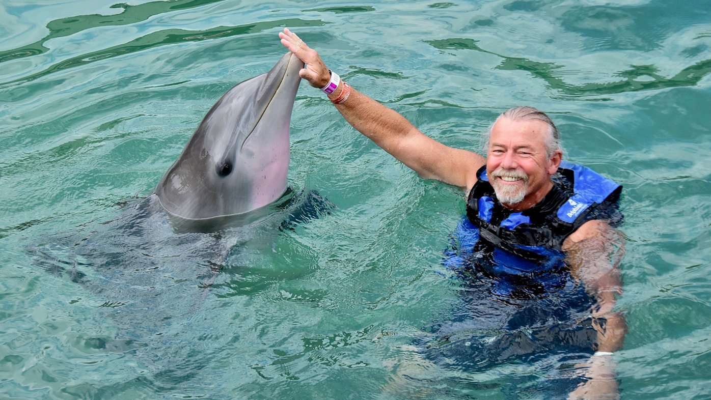 Mike Burge of San Diego in a life vest swimming with a dolphin