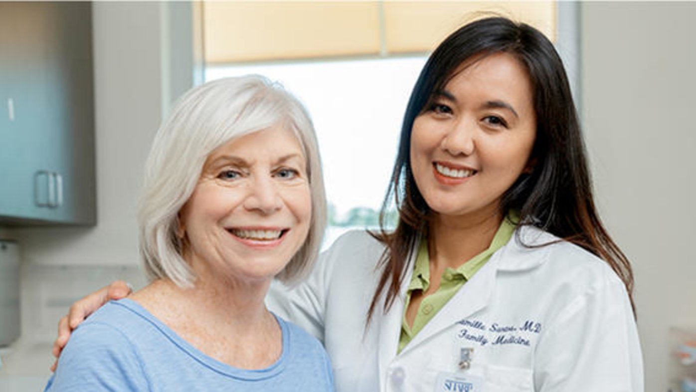Dr. Camille Santos, family medicine physician, with an older female patient wearing a blue shirt.