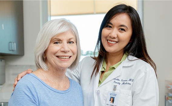 Dr. Camille Santos, family medicine physician, with an older female patient wearing a blue shirt.
