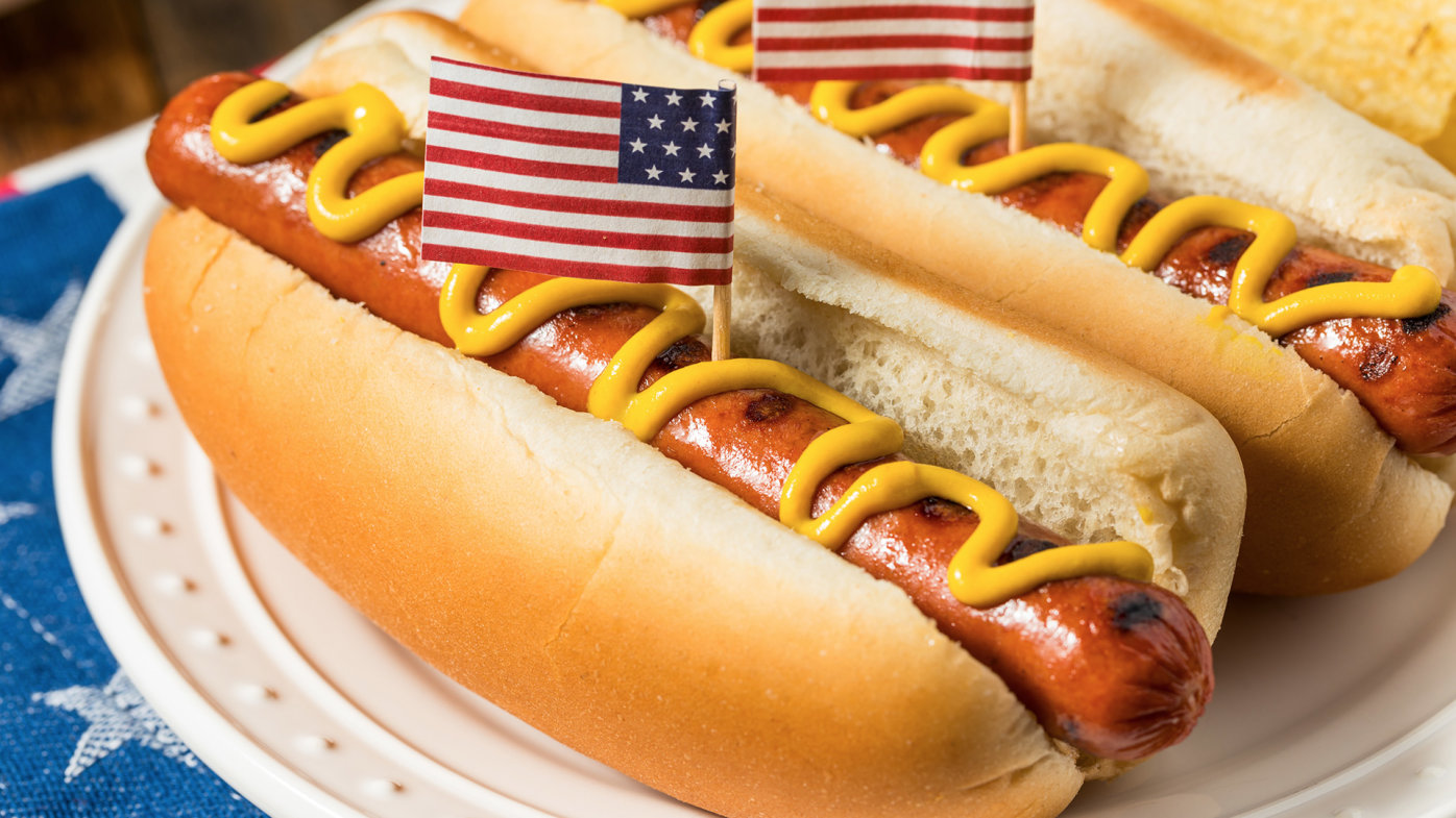 Hot dogs with mustard on a plate with American flag toothpick