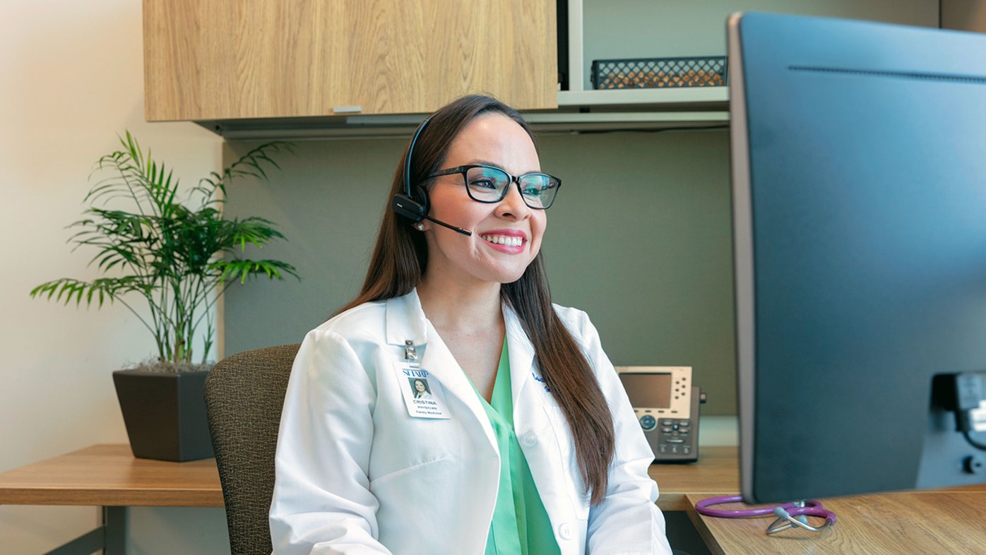 Dr. Coronado smiling and looking at computer monitor.