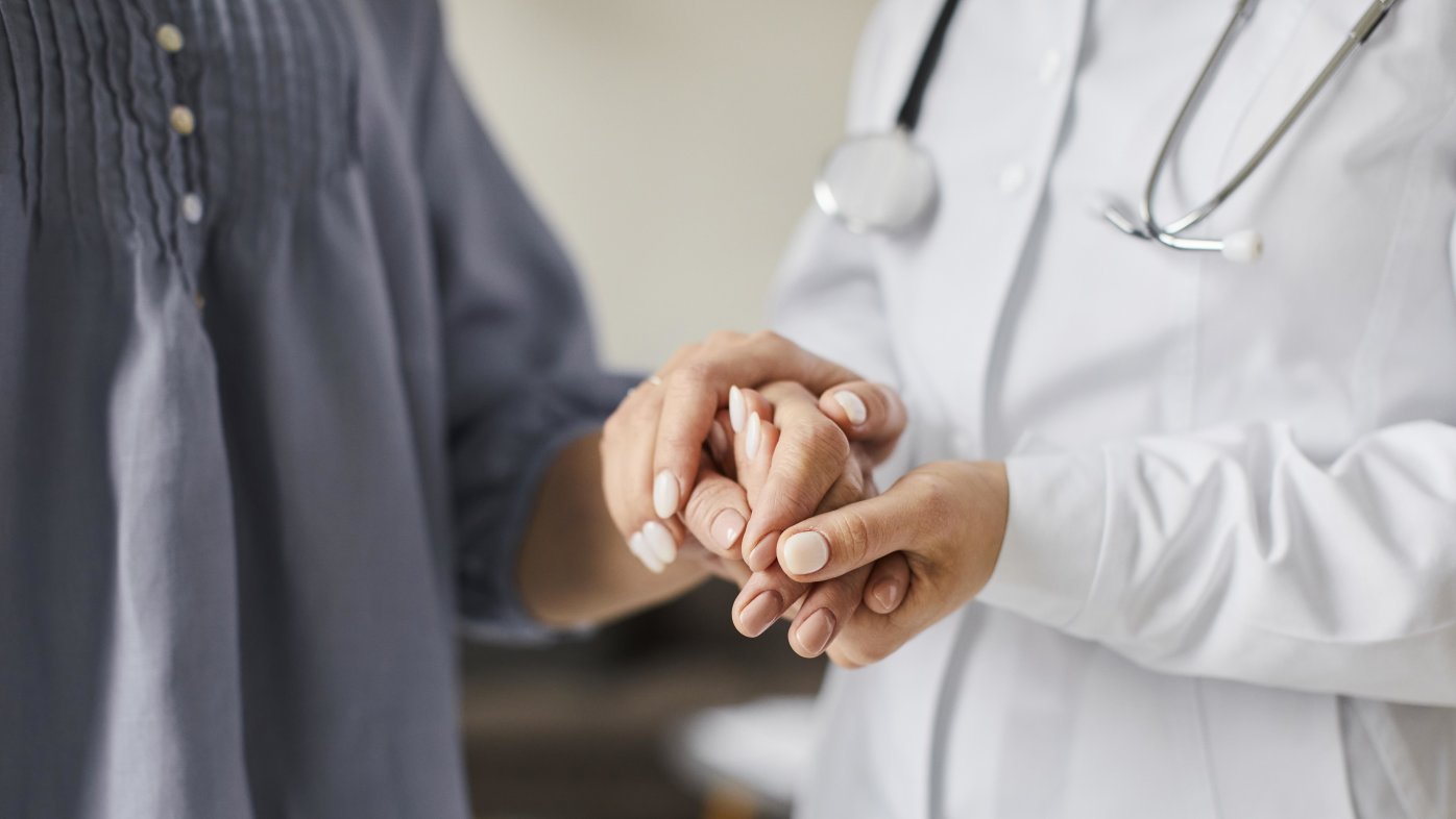 female doctor holding patient hands
