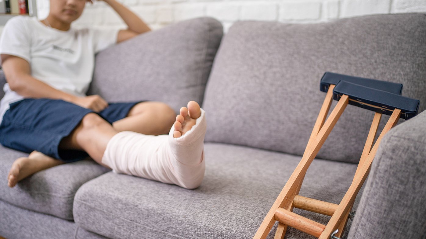 Person on the couch with leg cast and crutches