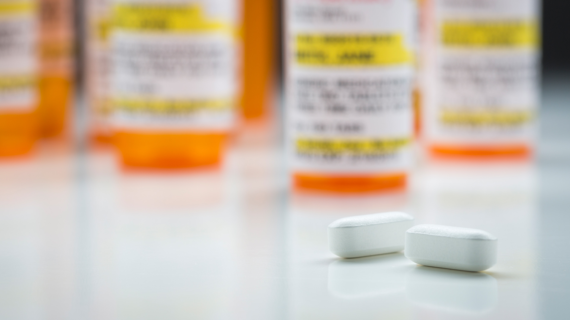 Bottles of prescription medication with two white pills