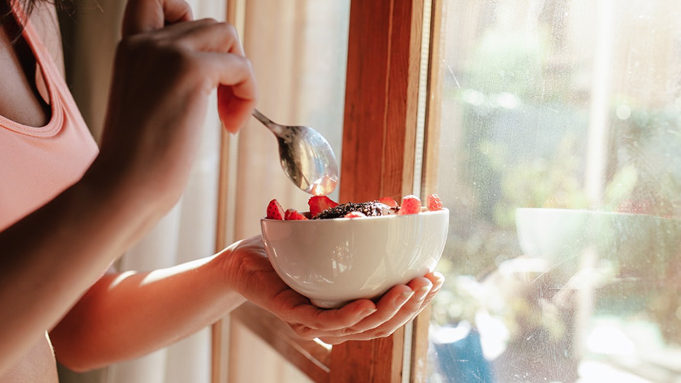 Woman eating healthy breakfast fruit bowl