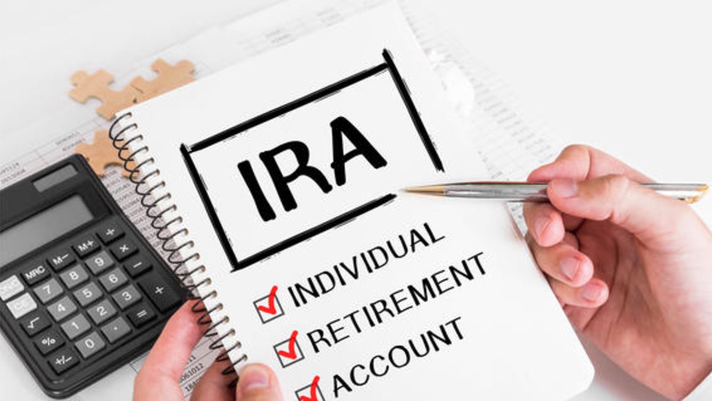Hands holding a notepad with IRA definition and silver pen