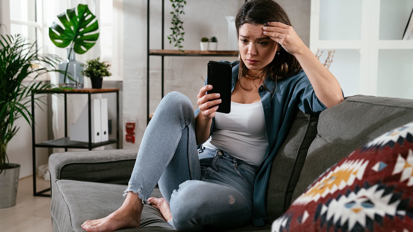 Stressed woman on a couch looking at her phone