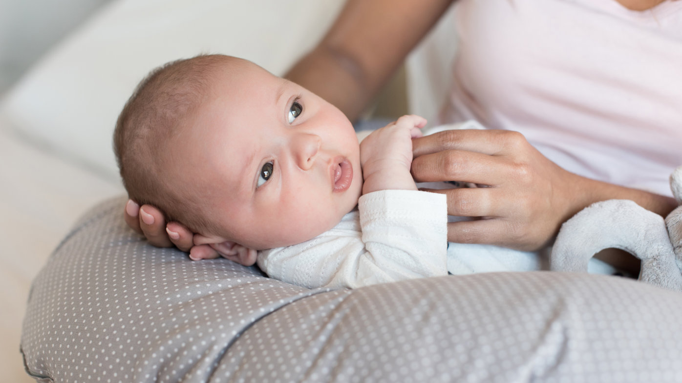 Mother holding her baby on a nursing pillow