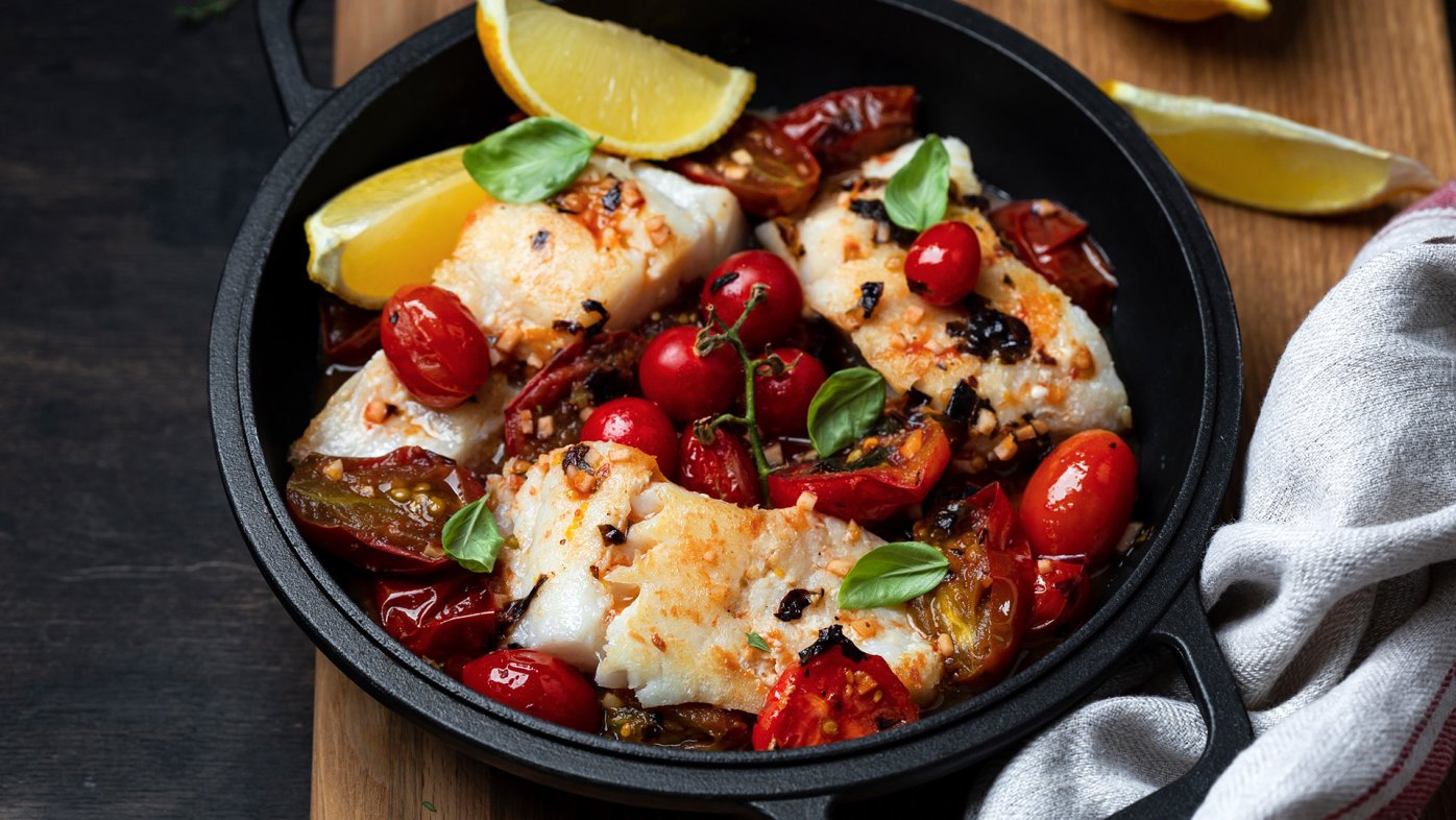 Fish and tomatoes meal with lemon in a skillet