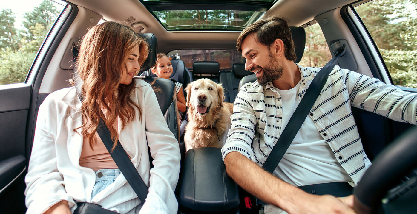 Family in car on road trip with dog
