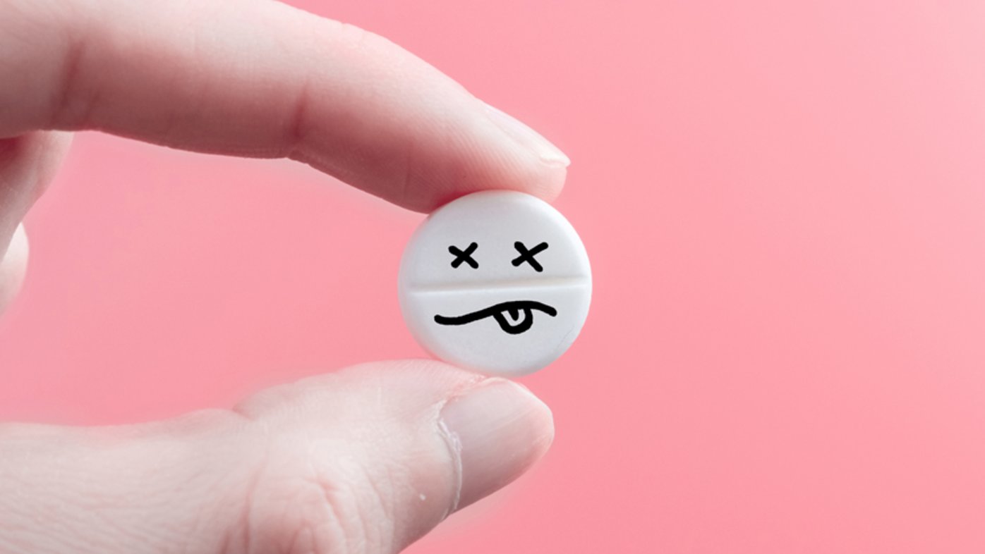 White pill with sad face drawn on it