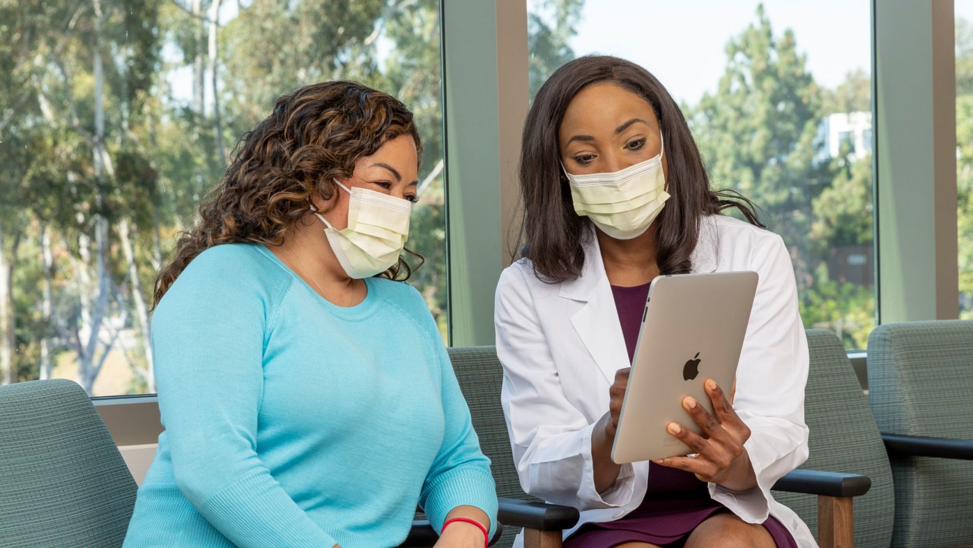 Doctor pointing to a tablet while consulting with smiling patient.