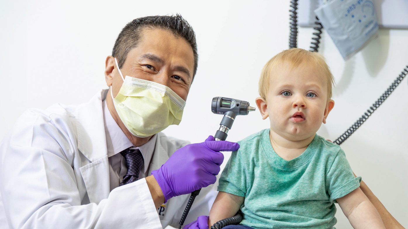 Dr. Lam about to examine baby's ear.