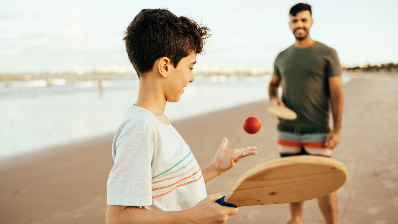 Father and son playing paddle ball on the beach