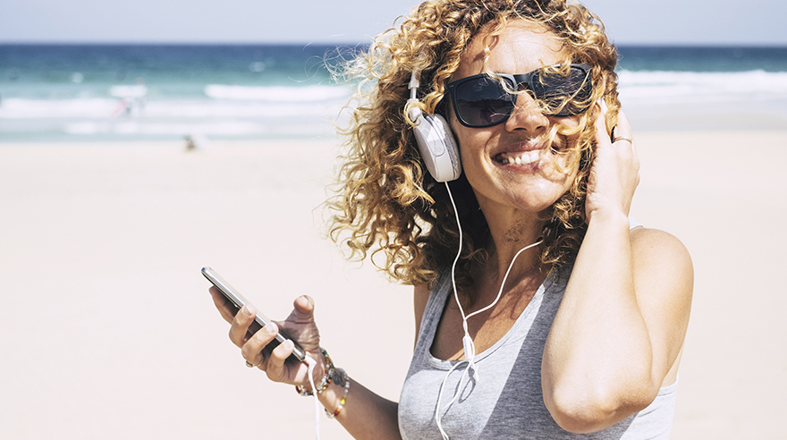 Mujer escuchando música en la playa