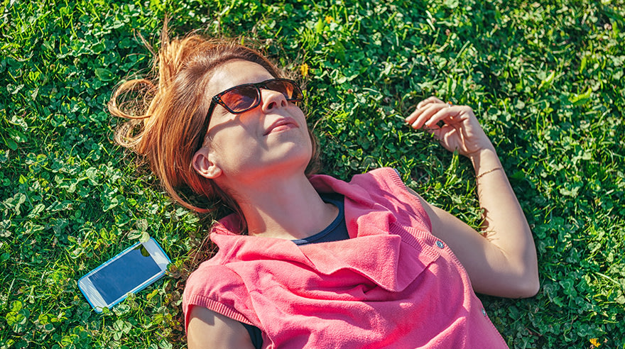 Woman with sunglasses lying in grass