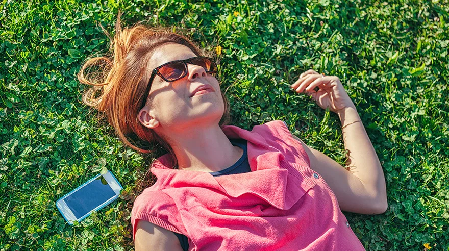 Woman with sunglasses lying in grass