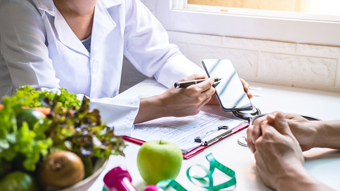 Nutritionist giving consultation to patient with healthy fruit and vegetable