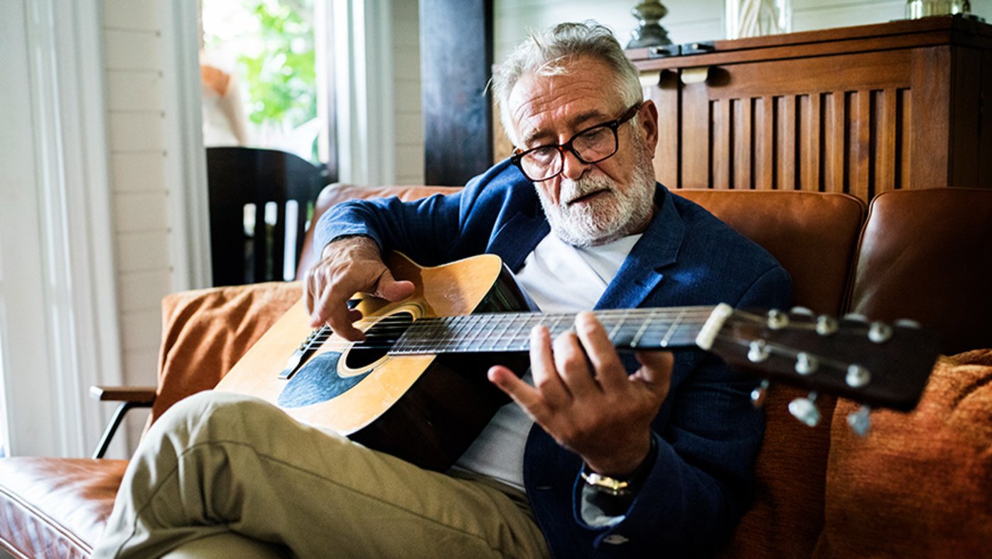 Man playing the guitar while sitting on a couch