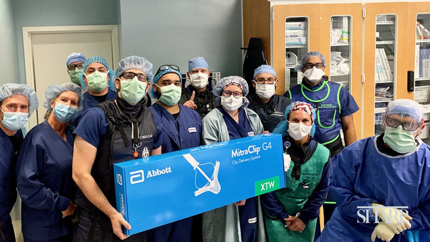 Dr. Jad Omran (left, in black vest), the Sharp Grossmont Hospital cardiac catherization lab team and representatives of Abbott pose with the MitraClip device, a minimally invasive treatment option for patients with mitral valve regurgitation.