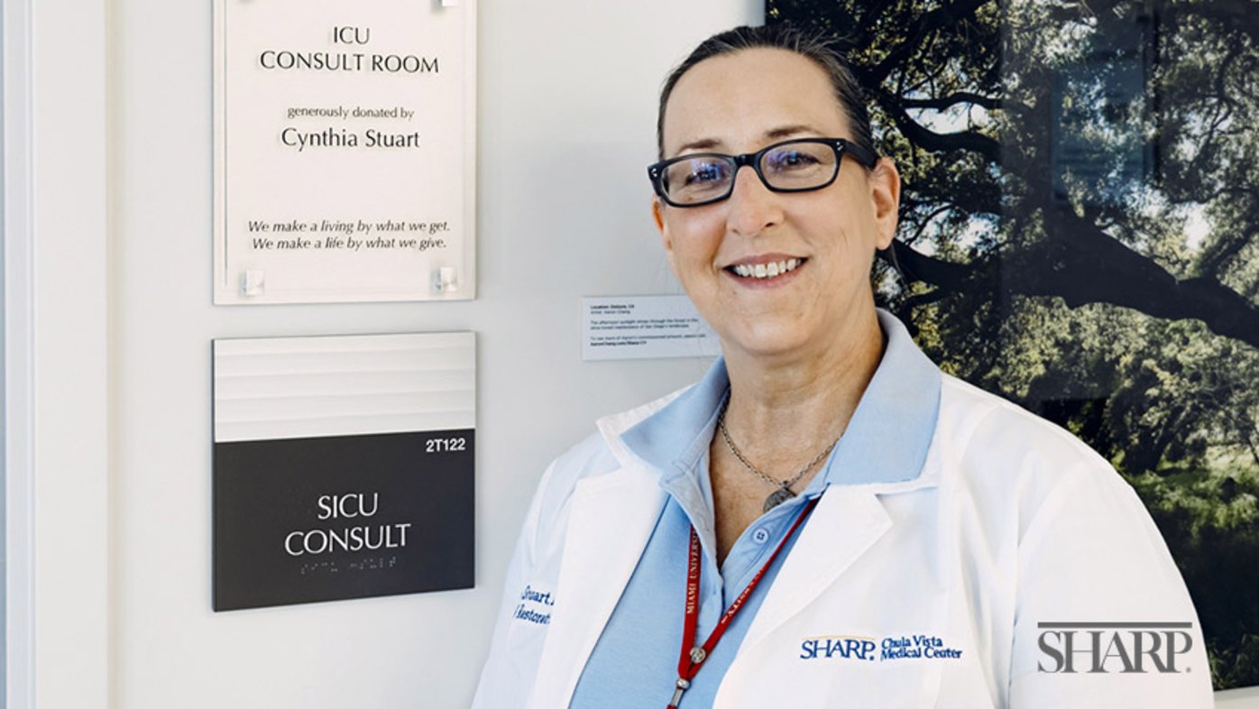 Cynthia Stuart stands proudly next to the plaque dedicated to her generous heart at Sharp Chula Vista.