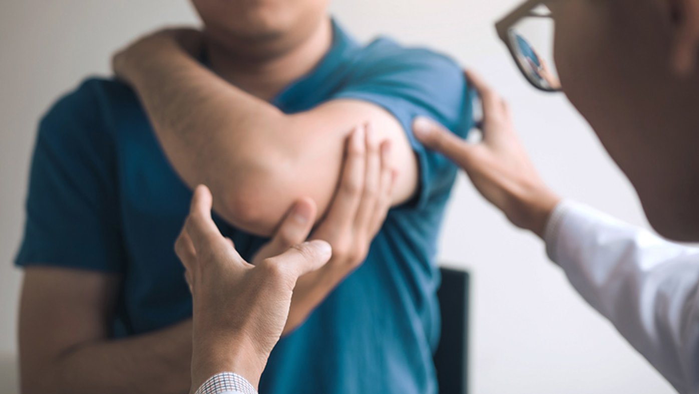 Doctor helping patient with his shoulder pain