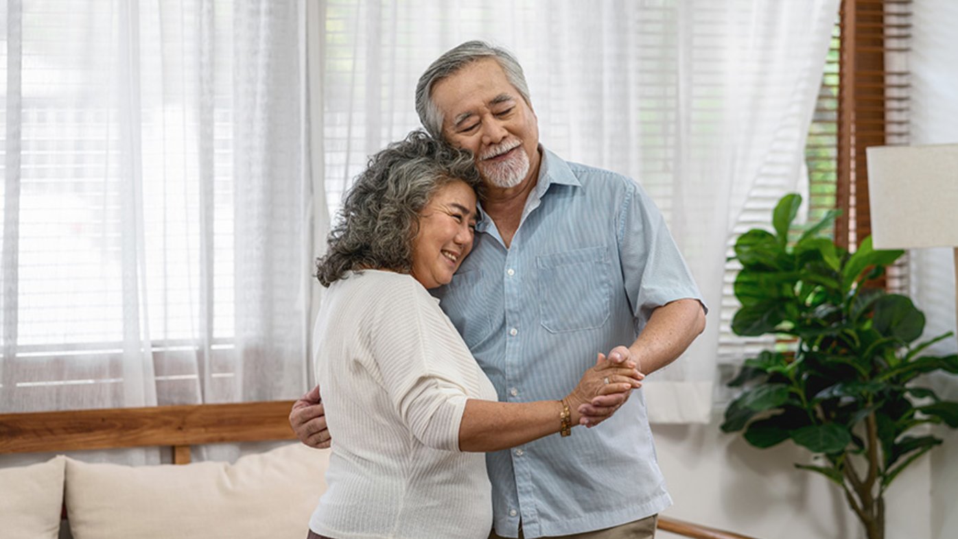 Grandparents dancing and hugging together with happy feeling in house