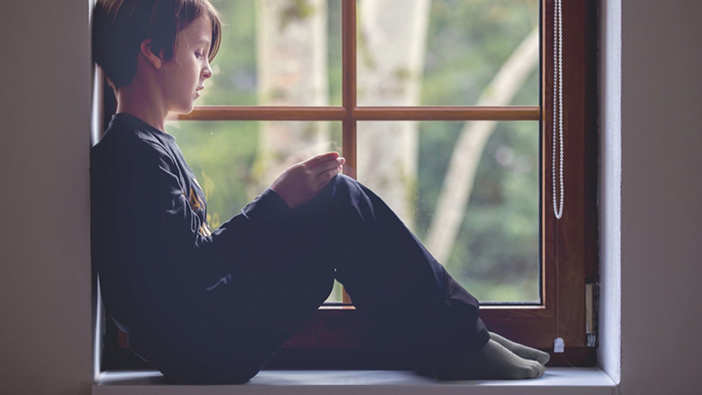 Sad boy sitting in window