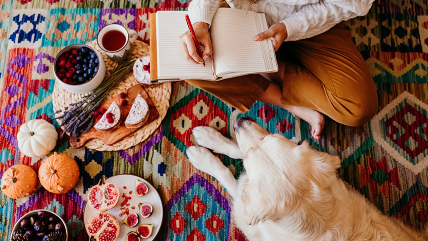 Woman writing in journal with dog