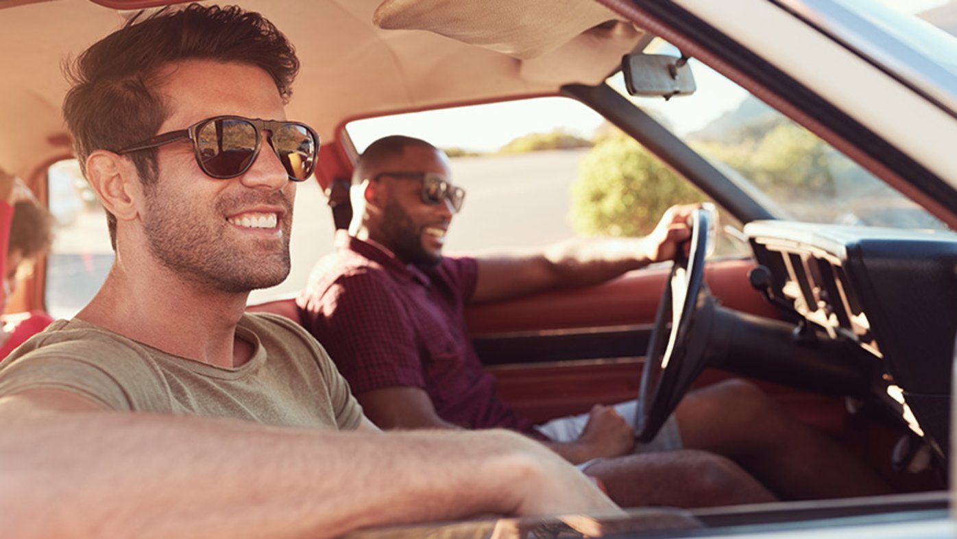 Two male friends relaxing in the car on a road trip.