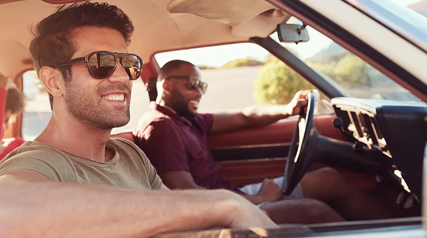 Two male friends relaxing in the car on a road trip.