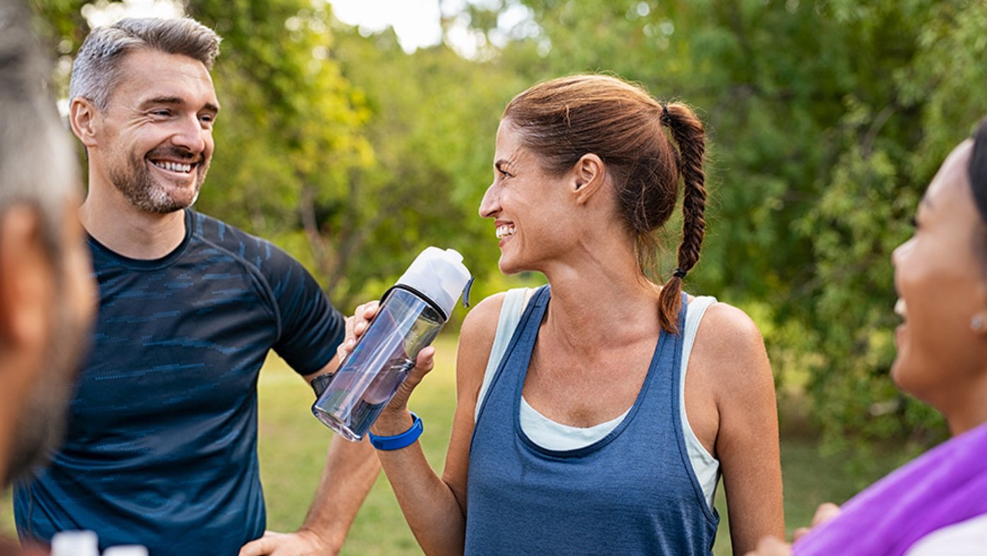 Friends exercising outdoors while drinking water