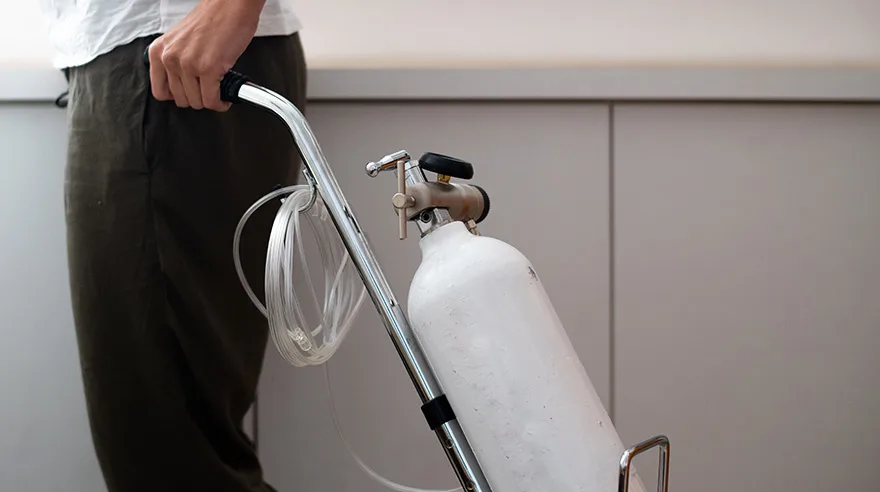 Woman is holding portable oxygen gas cylinder for use at home.