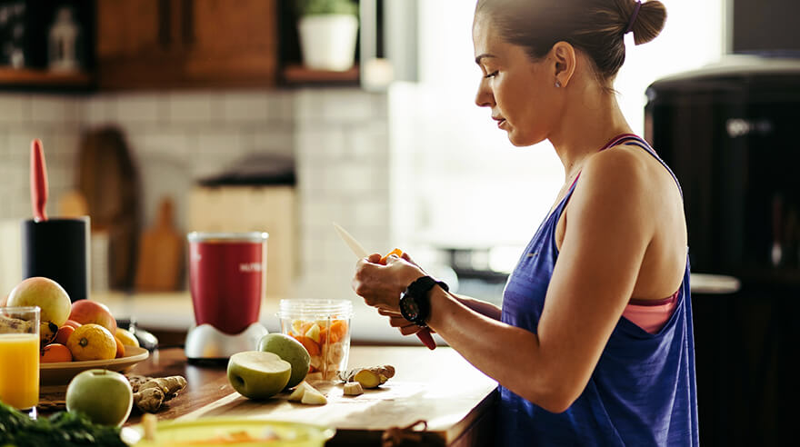Active woman cutting fruit for smoothie