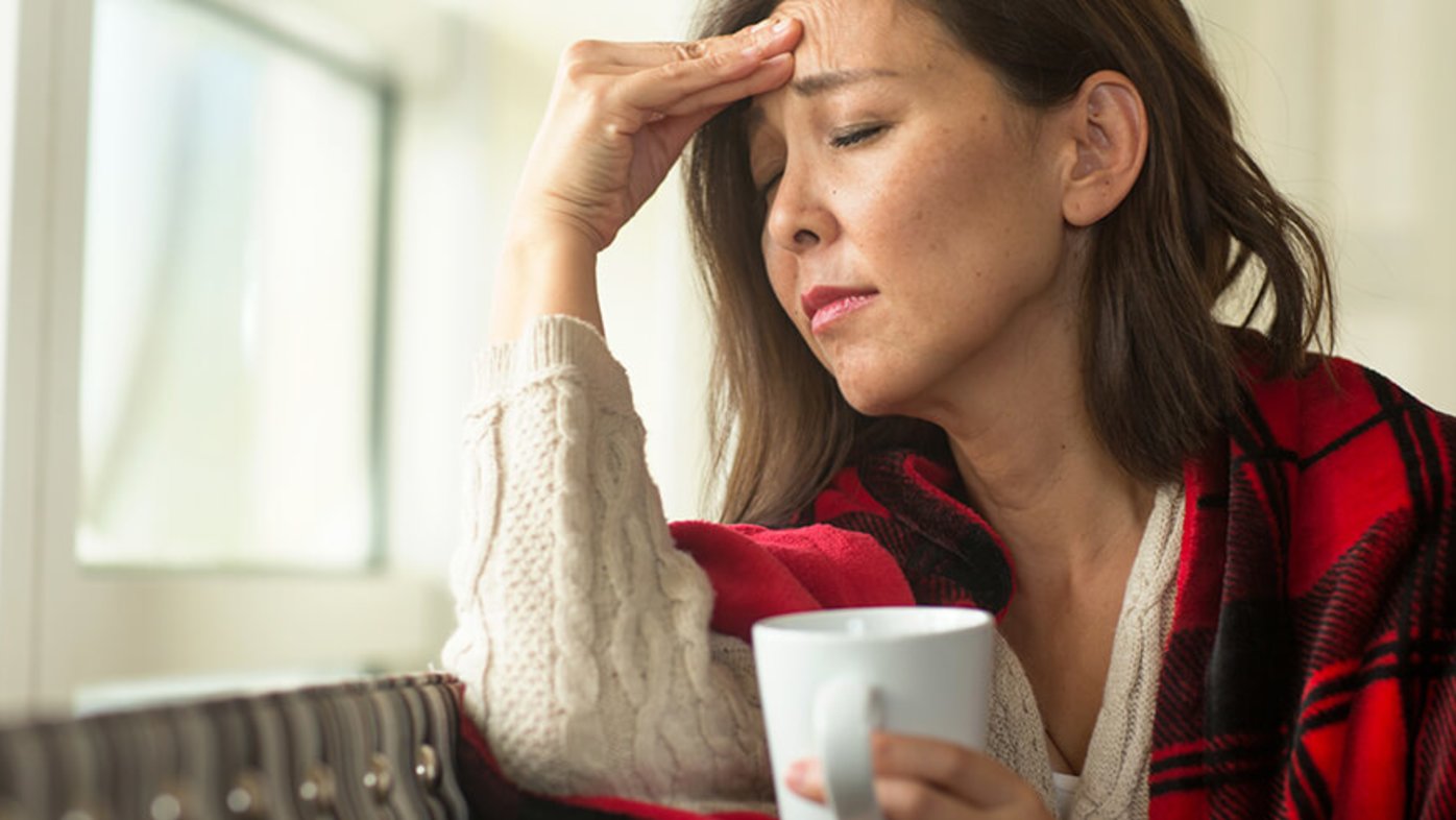 Woman holding her forehead and a cup