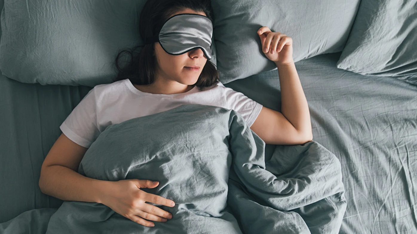 Woman sleeping in bed wearing eye mask