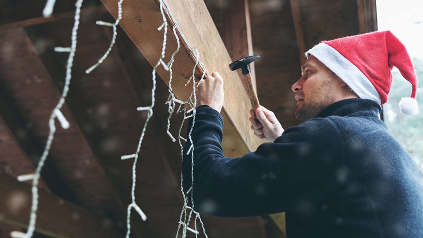 Man on ladder decorating house for holidays