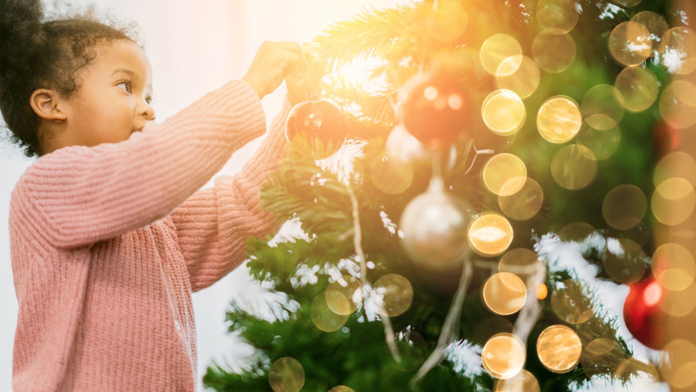 Child putting decorations on a Christmas tree