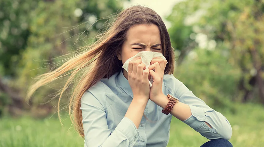 Woman sneezing outside in park