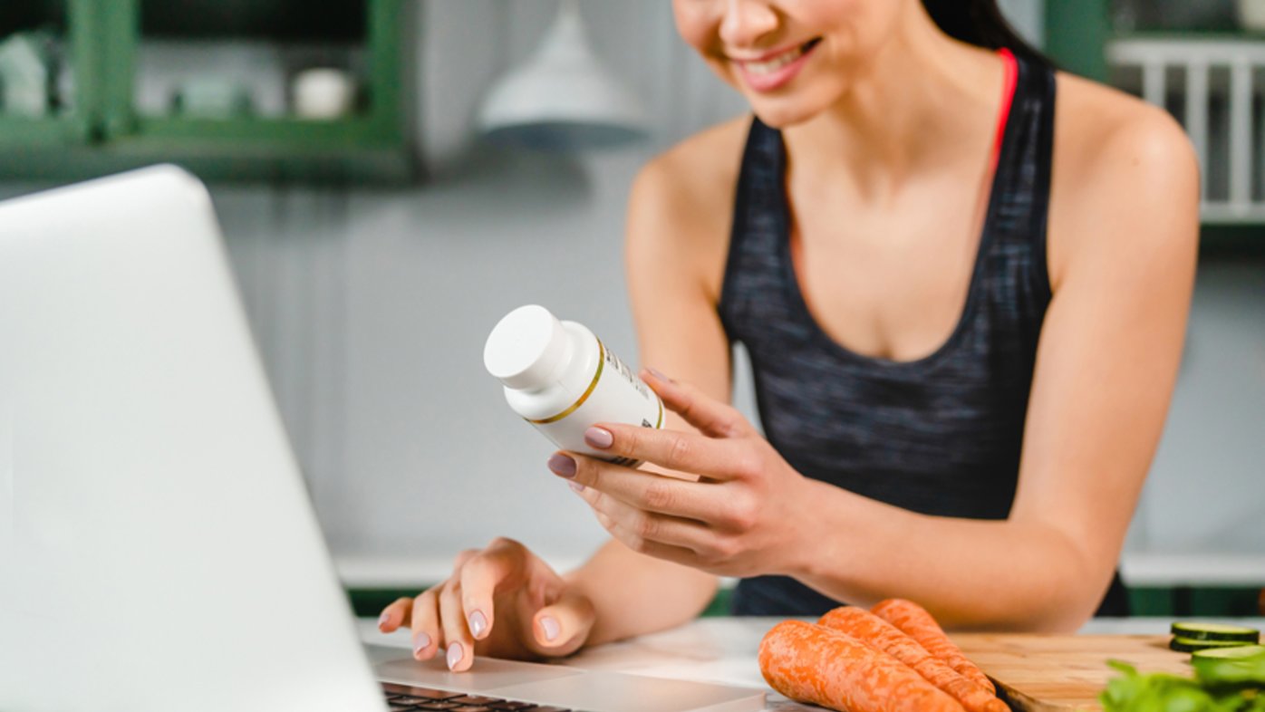 Woman reviewing information on bottle of vitamins