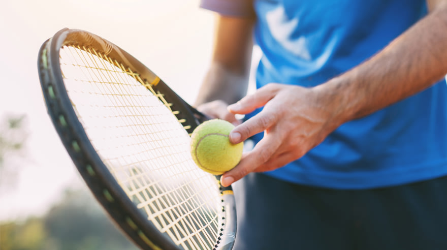 Athlete holding tennis racquet and ball