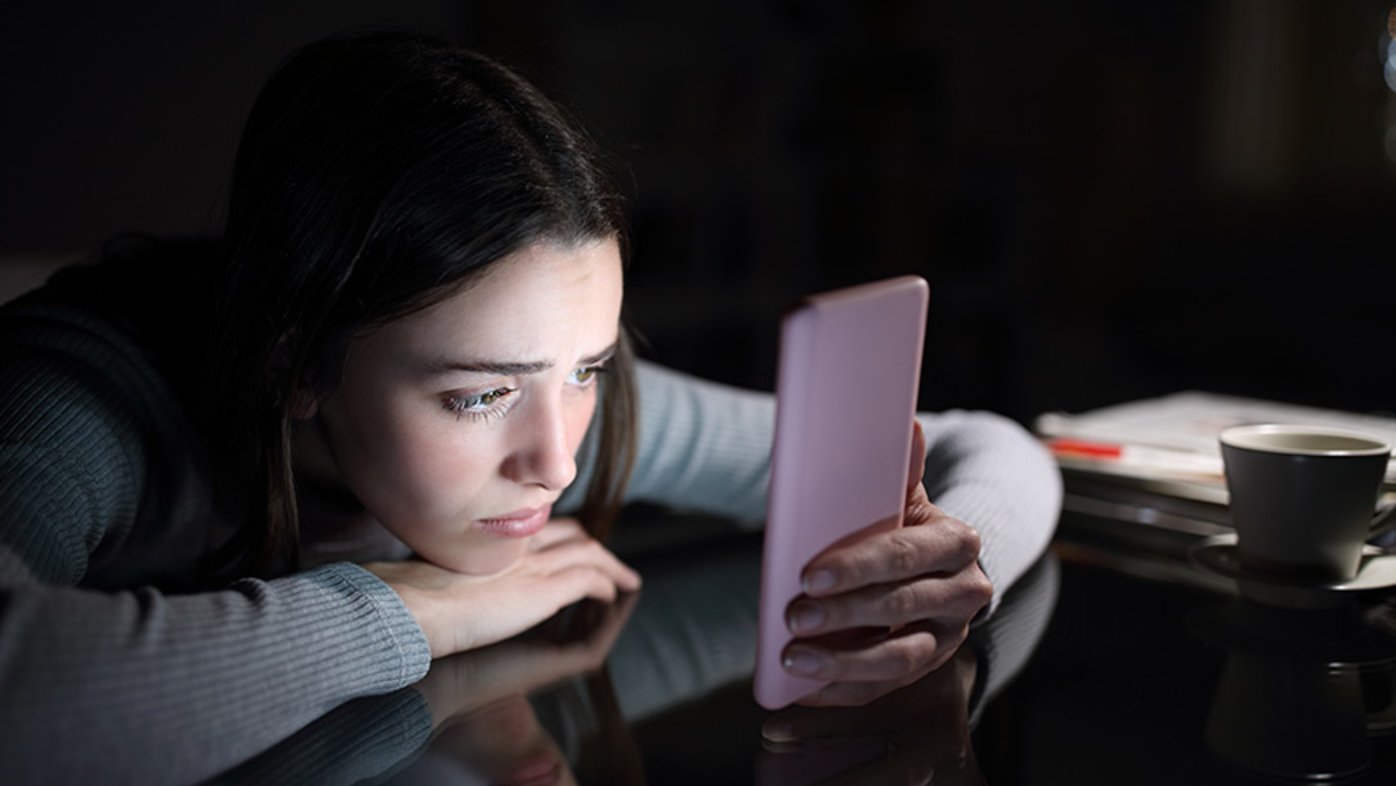 Young girl reads her phone in the dark