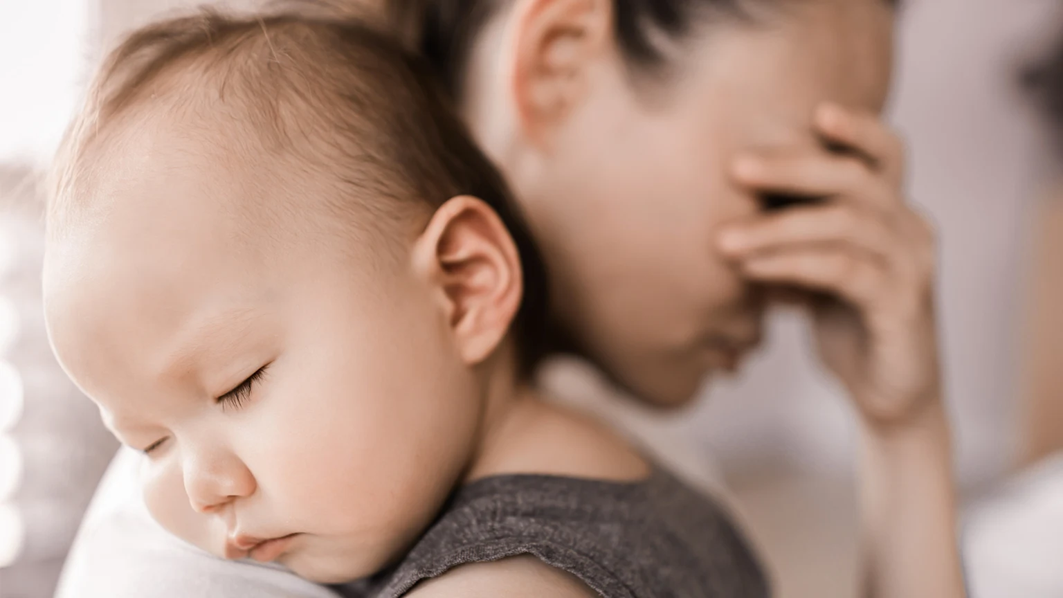 Sad woman holding her sleeping baby