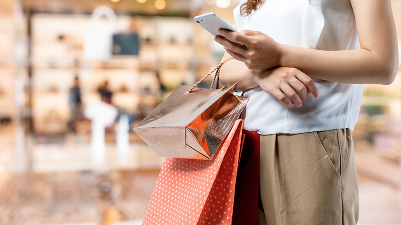 Person shopping at the mall with packages and a cell phone