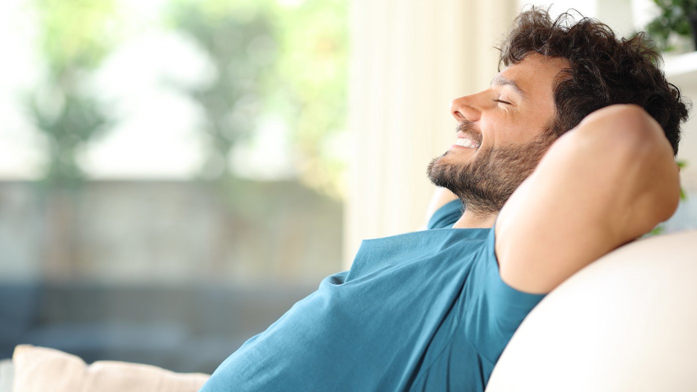 Man relaxing on the couch with his arms behind his head