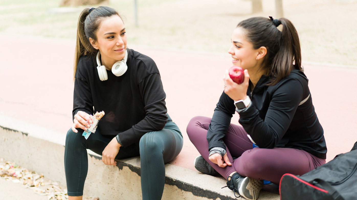 Two friends eating snacks after exercising