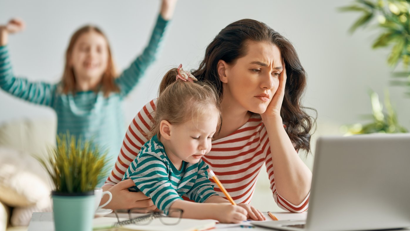 Stressed mother with two kids reading laptop computer