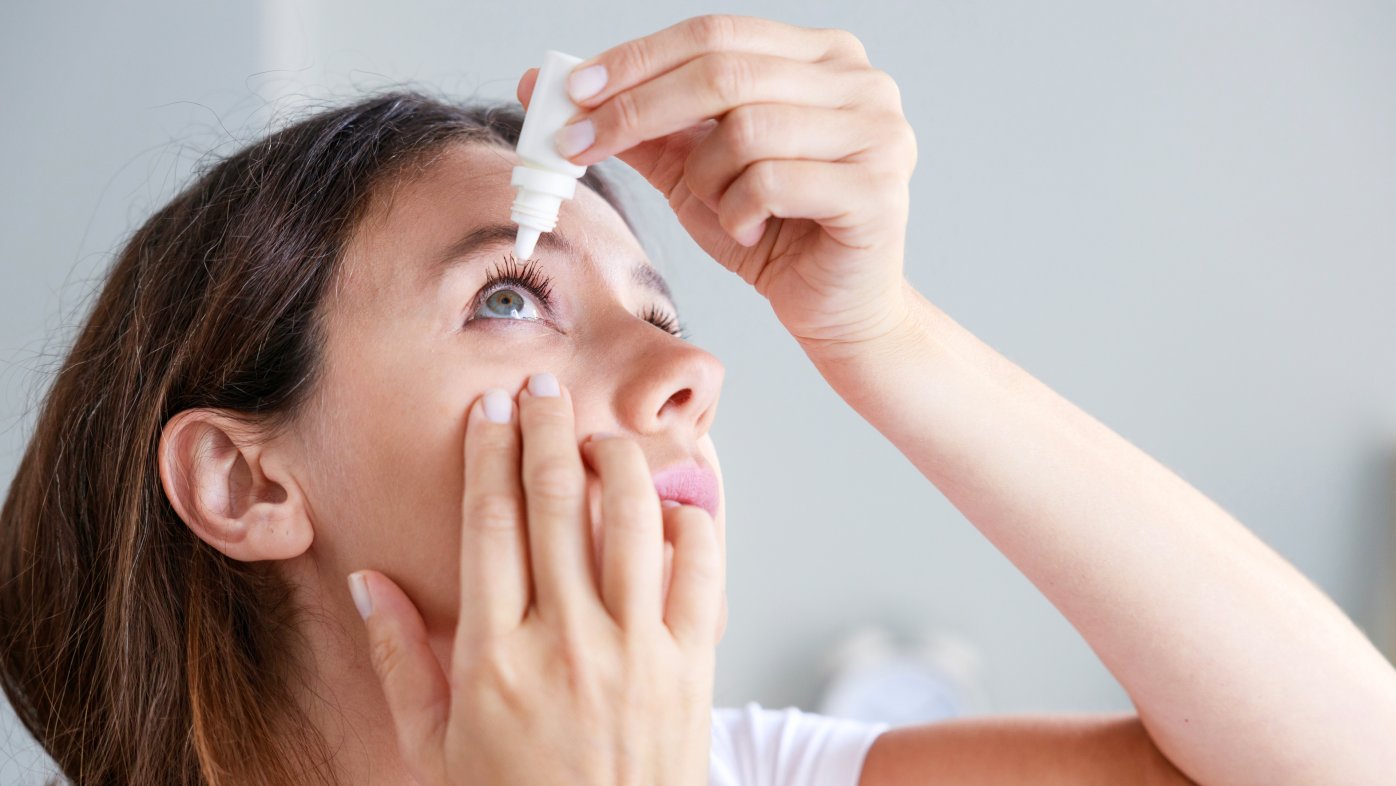 Woman putting eye drops in her eye