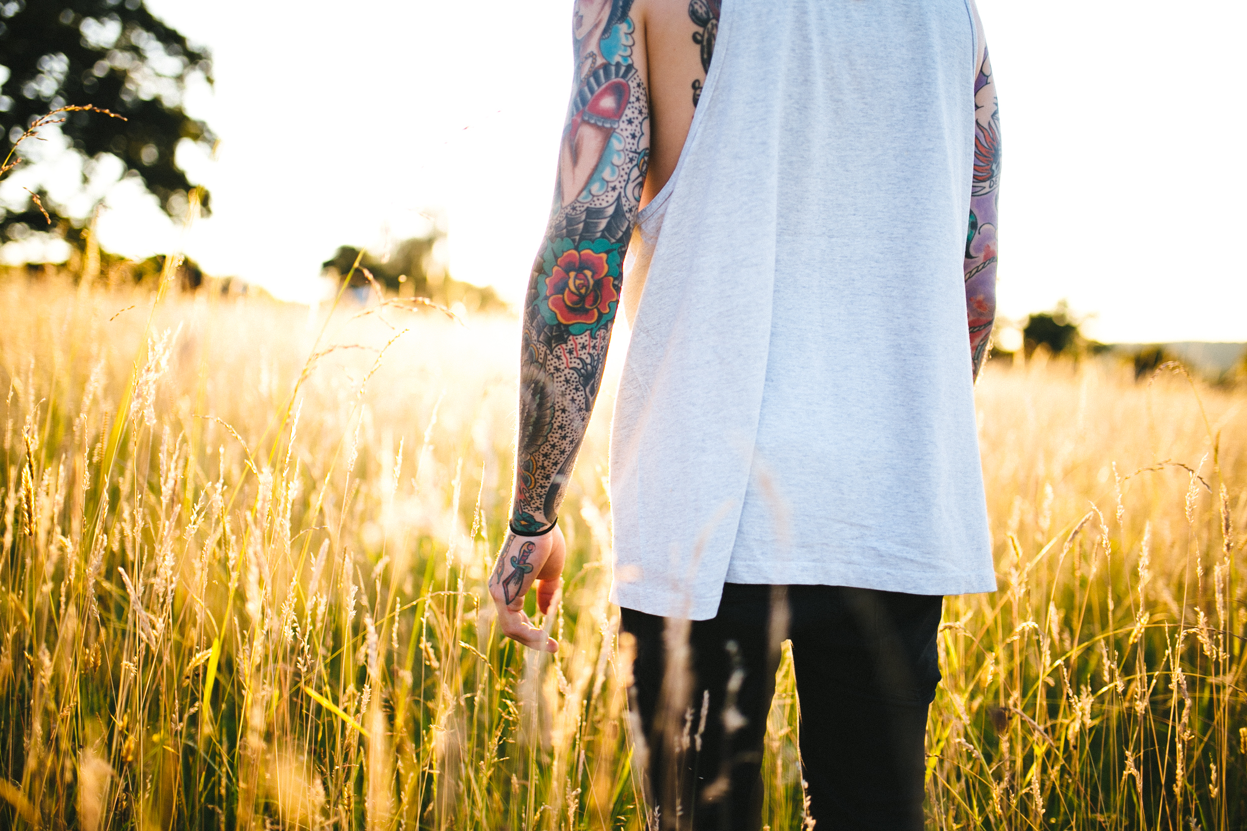 Tattooed man walking in a field