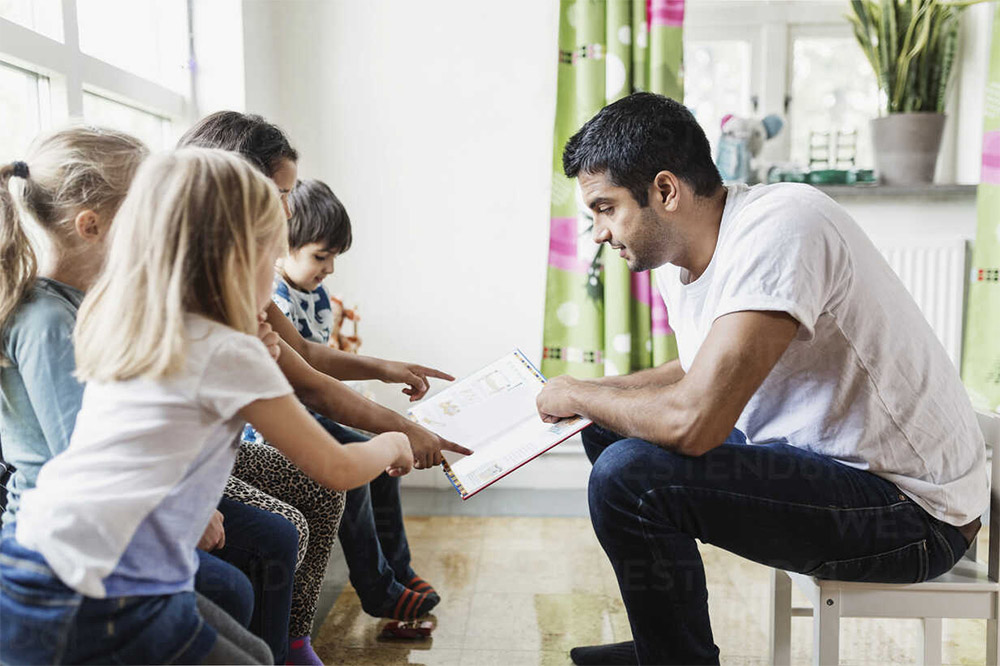 Erzieher liest Kindern vor